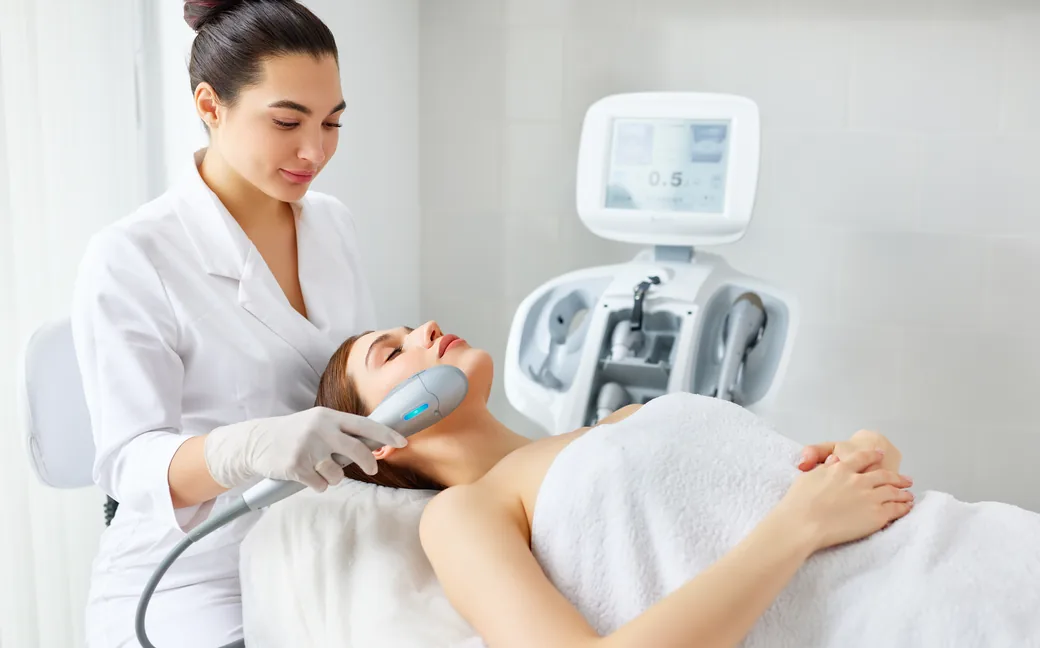 Therapist performing a facial treatment with a skin device